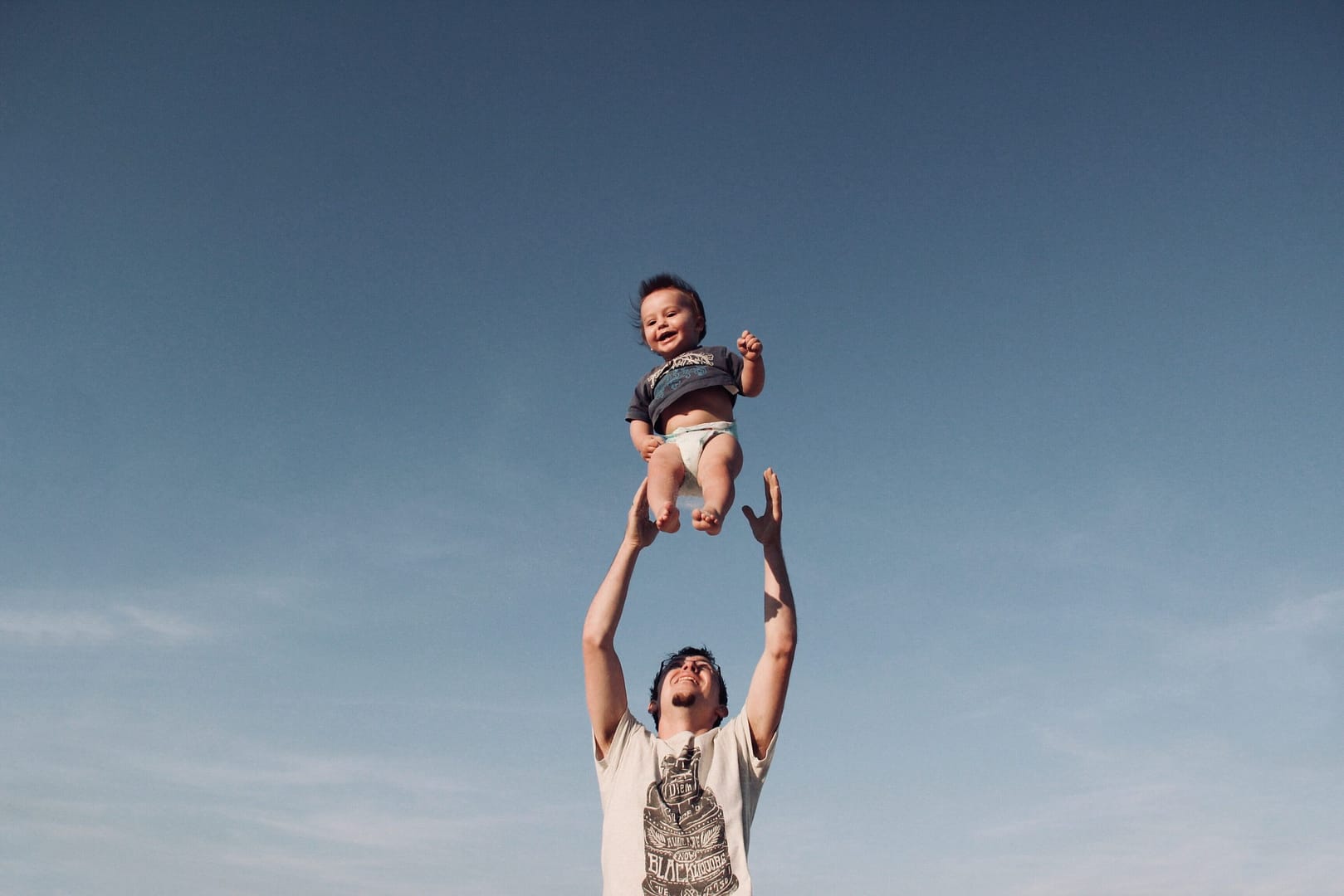 Man tossing happy baby up into the air
